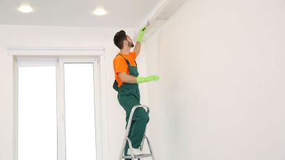 Professional painter on a ladder adding final paint details to a ceiling