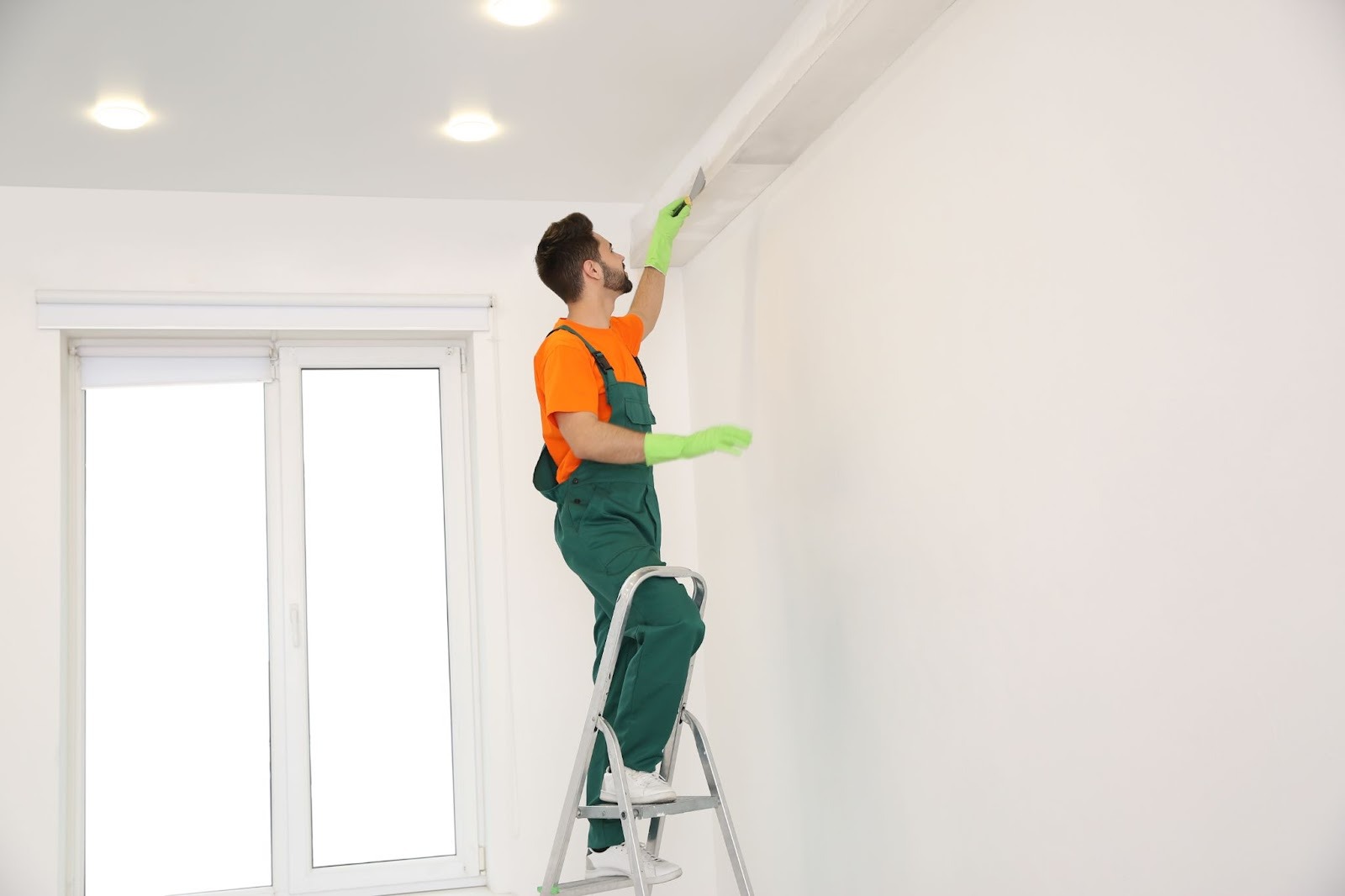 Professional painter on a ladder adding final paint details to a ceiling