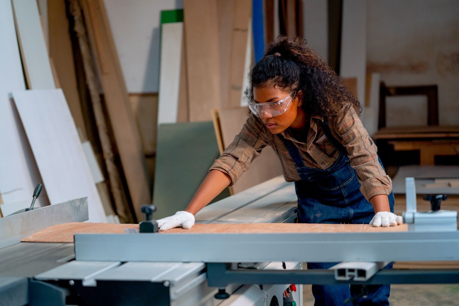 Female carpenter checking precision cutting machinery while working on custom woodworking projects
