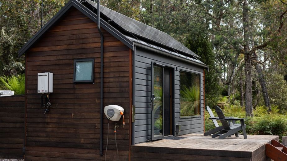 A detached accessory dwelling unit built as a small cabin in a spacious residential backyard