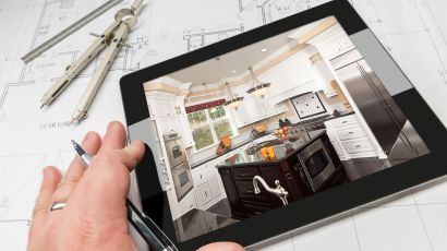 Contractor reviewing a kitchen remodel image on a tablet above blueprints
