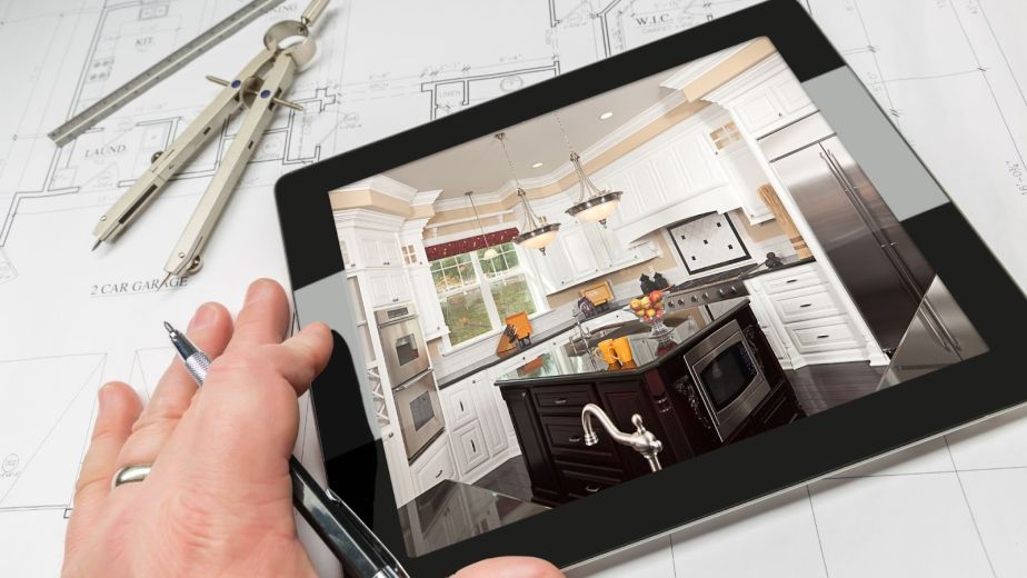 Contractor reviewing a kitchen remodel image on a tablet above blueprints