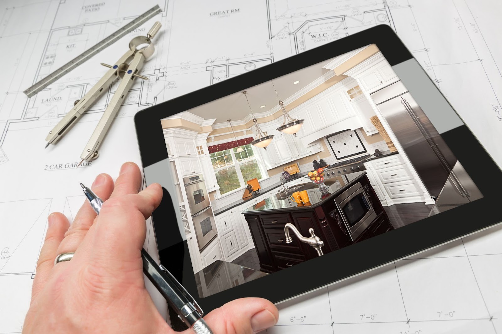 Contractor reviewing a kitchen remodel image on a tablet above blueprints