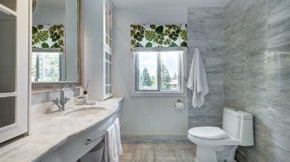 Elegantly remodeled bathroom with gray wall tiles and leaf-patterned window blinds