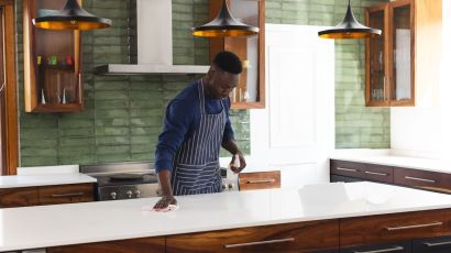 A worker from a kitchen remodeling company cleans a newly installed quartz countertop with a spray bottle and a cloth