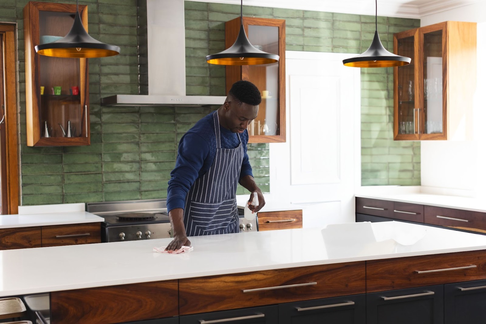 A worker from a kitchen remodeling company cleans a newly installed quartz countertop with a spray bottle and a cloth