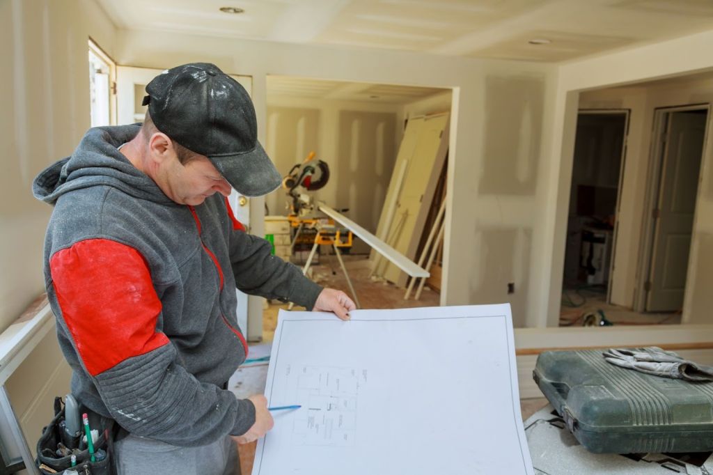 Seismic retrofit engineer marking construction blueprints to improve residential earthquake resistance.