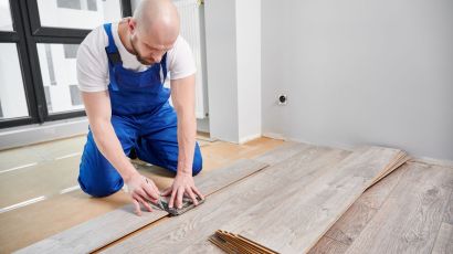 A skilled installer draws a guideline on a laminate plank for precise floor installation