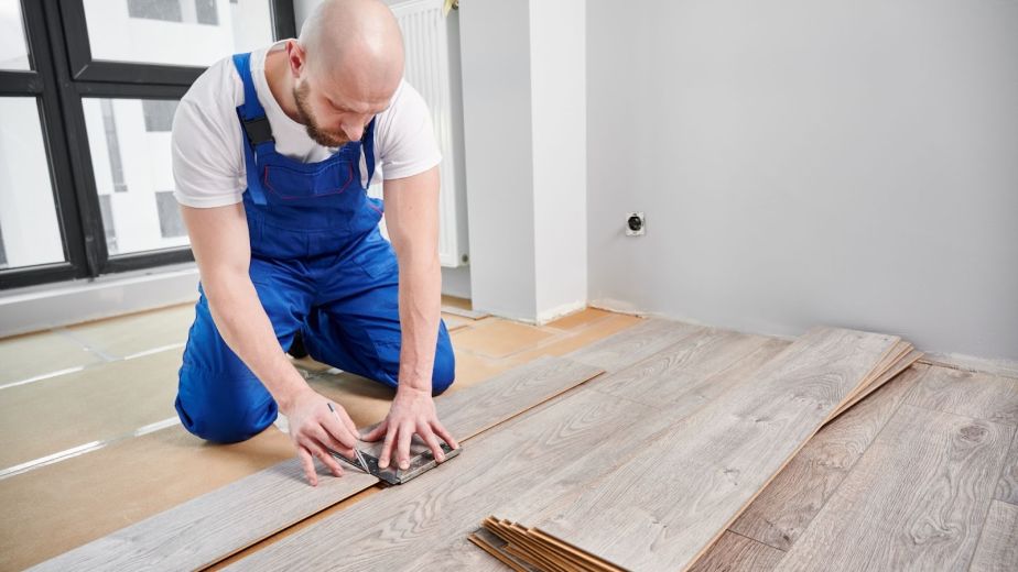 A skilled installer draws a guideline on a laminate plank for precise floor installation