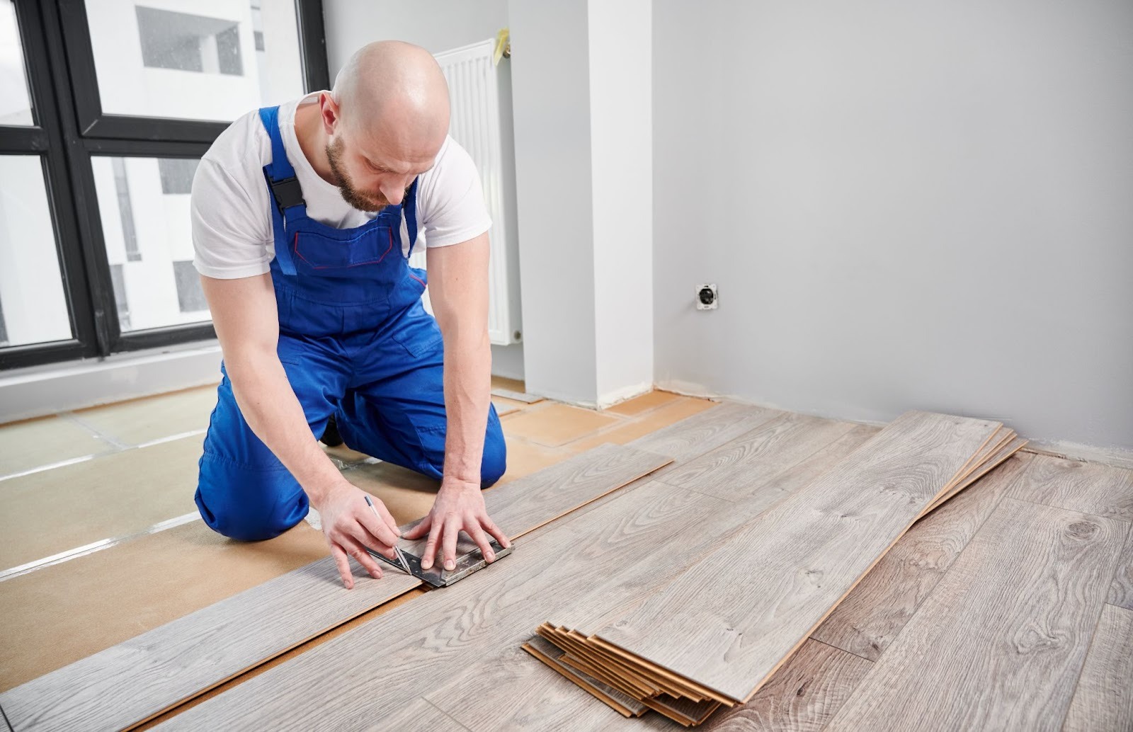 A skilled installer draws a guideline on a laminate plank for precise floor installation
