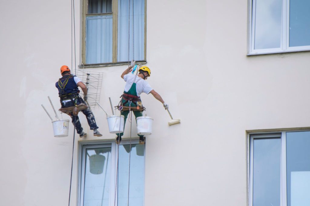 Exterior painting in progress with professional painters on harnesses