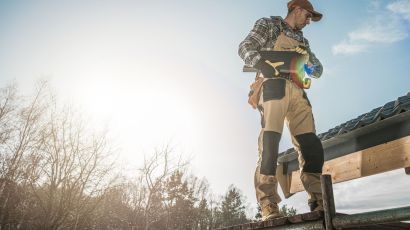 A professional roofer inspecting a residential roof for damage, leaks, and worn materials