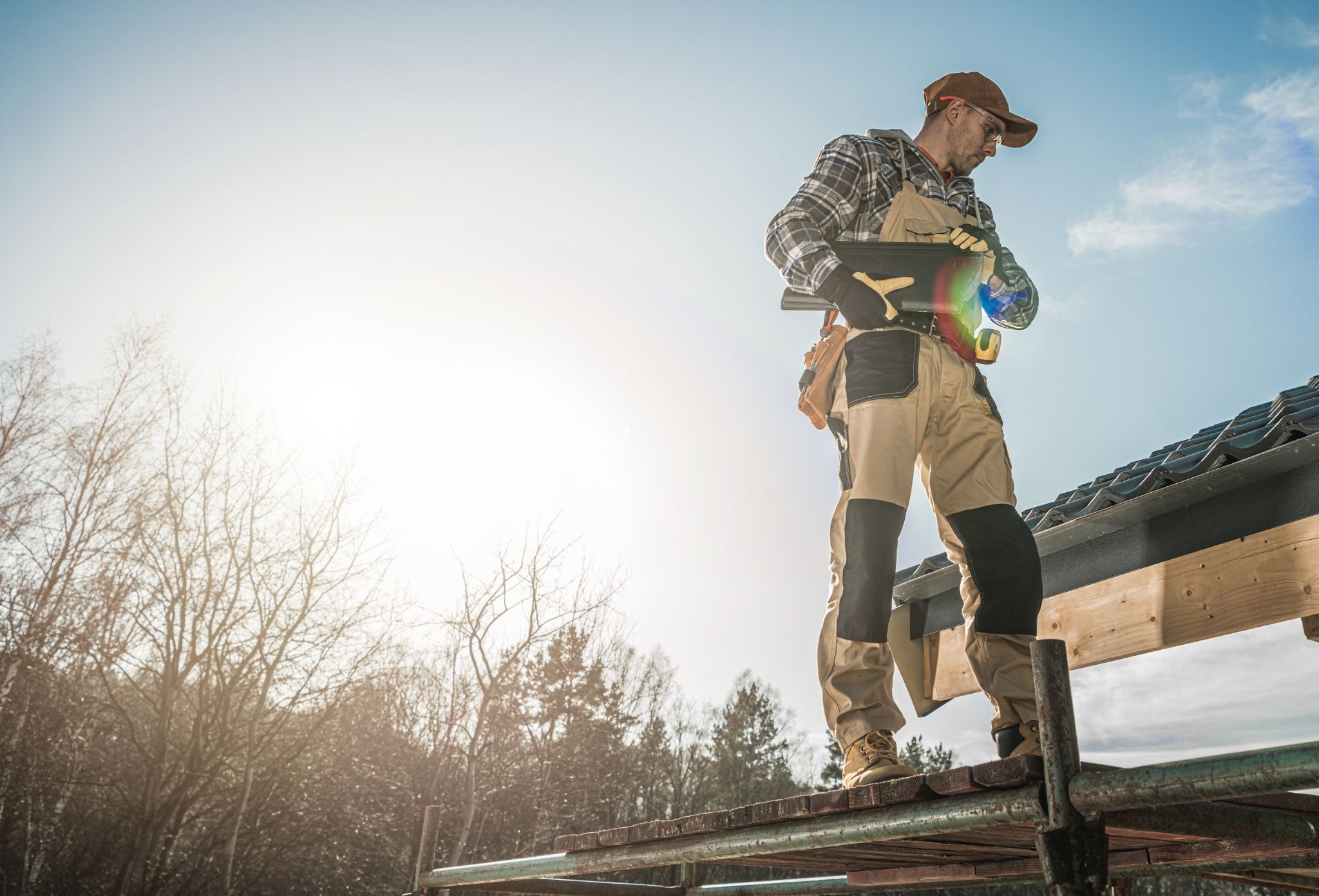A professional roofer inspecting a residential roof for damage, leaks, and worn materials