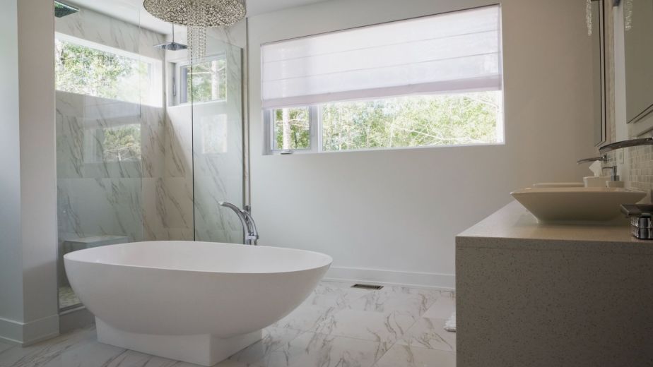 Bright and modern bathroom remodel featuring a freestanding bathtub, glass shower, and granite vanity