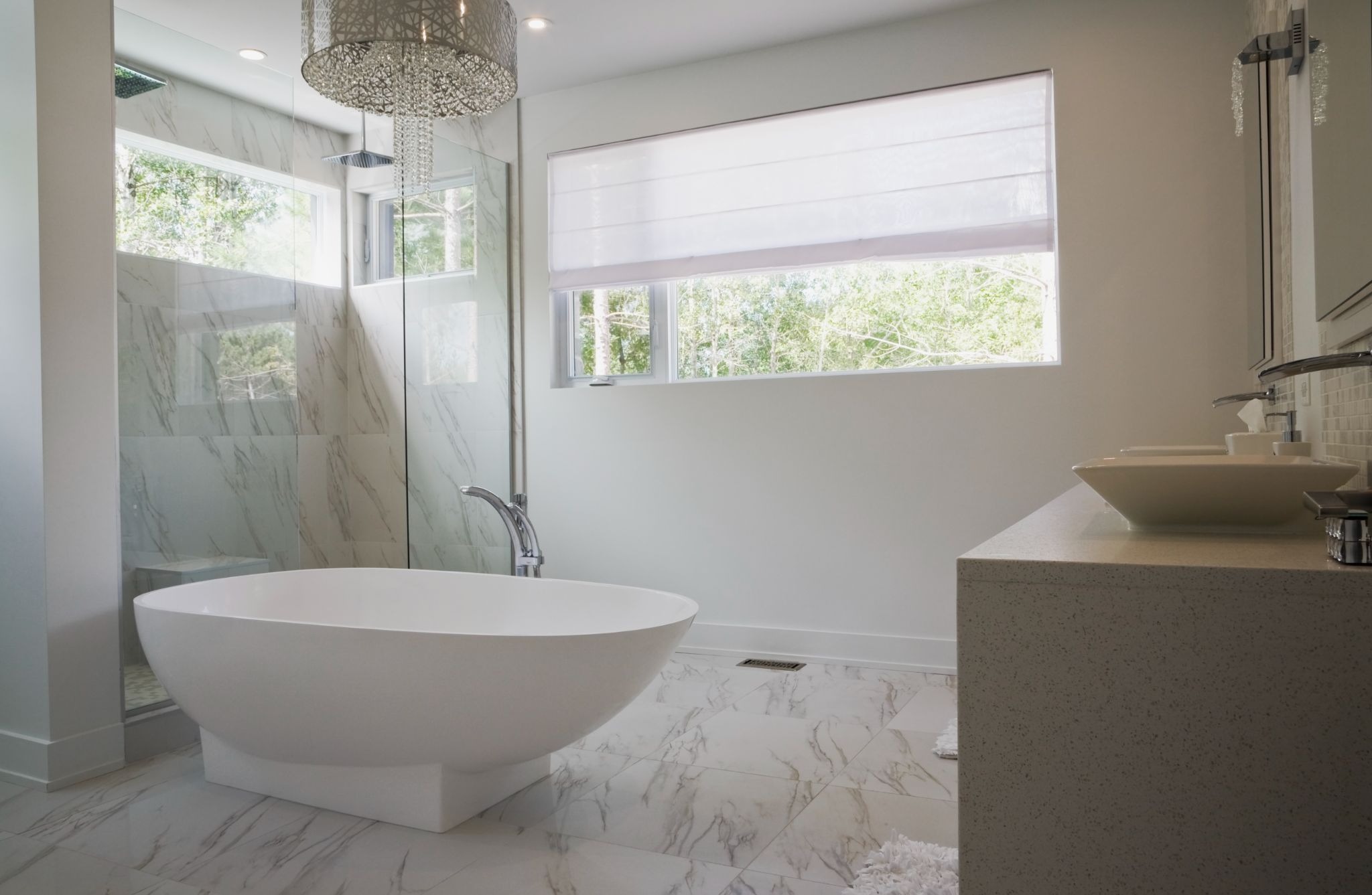 Bright and modern bathroom remodel featuring a freestanding bathtub, glass shower, and granite vanity