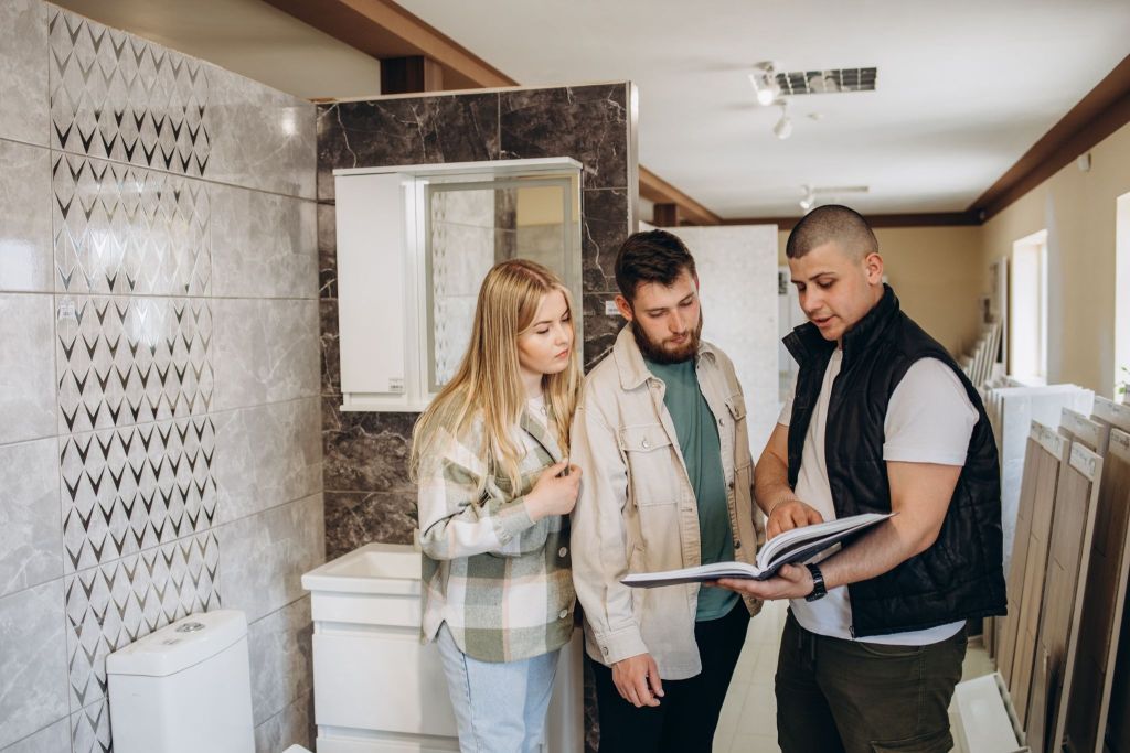 Couple reviewing bathroom material samples with a remodeling contractor while discussing bathroom remodeling costs