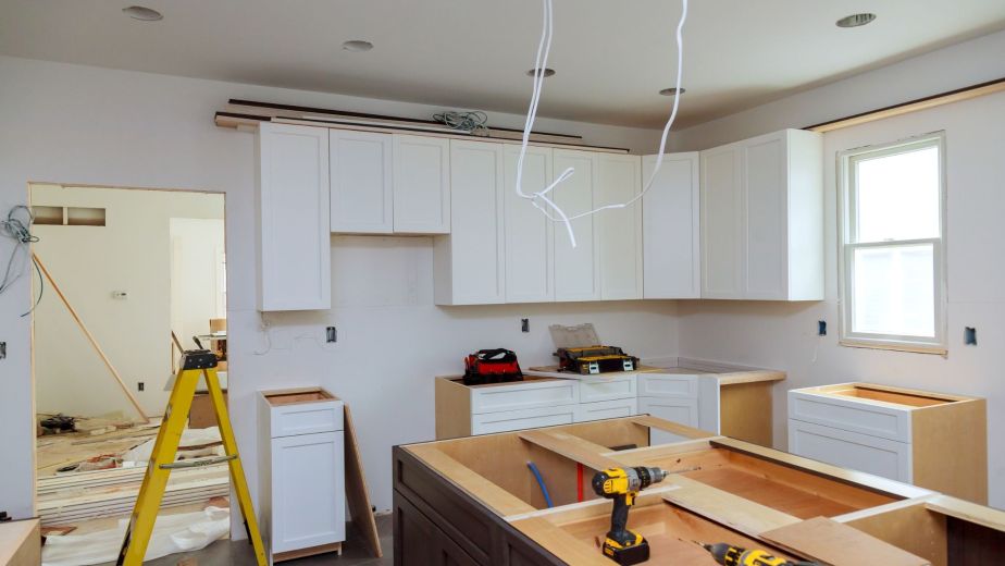 Kitchen remodeling project managed by general contractor services with modern white cabinets and ongoing construction