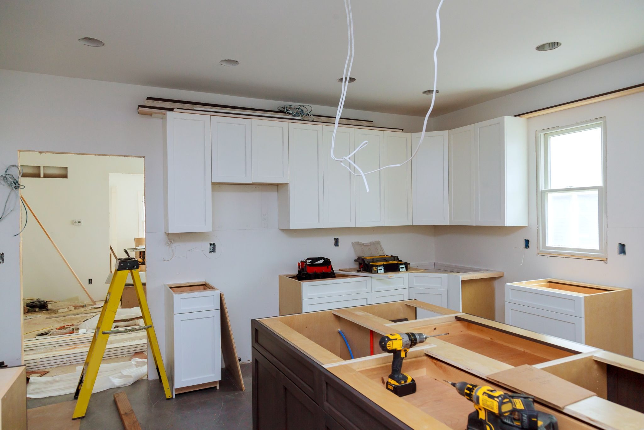 Kitchen remodeling project managed by general contractor services with modern white cabinets and ongoing construction