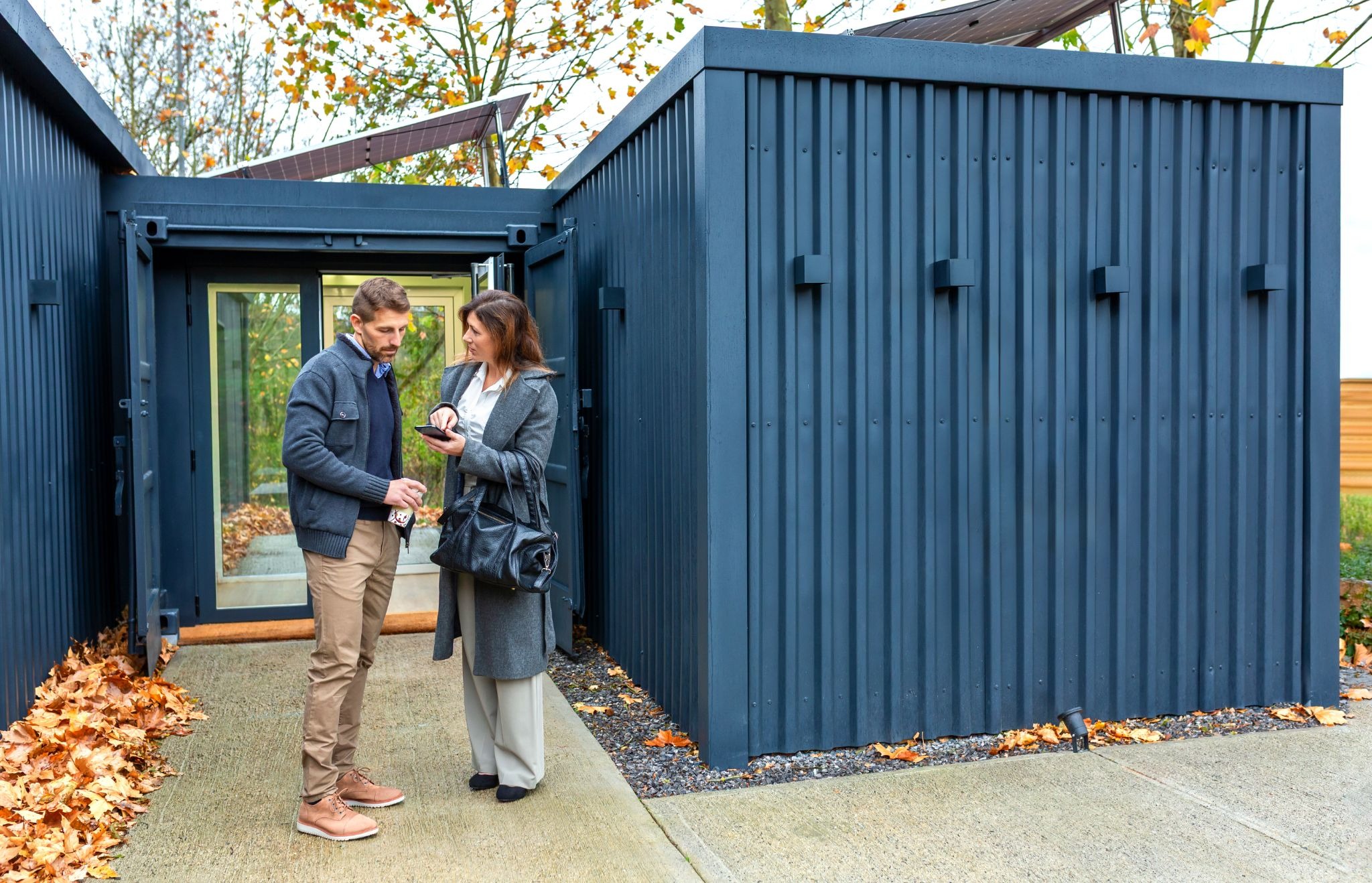 Homeowners discussing ADU design plans outside a modern residential property